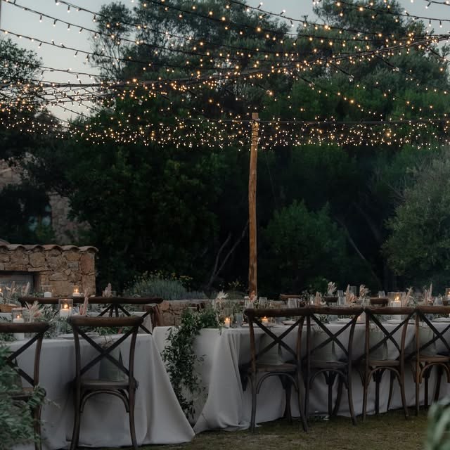 Longue table de réception éclairée par des guirlandes lumineuses en Corse